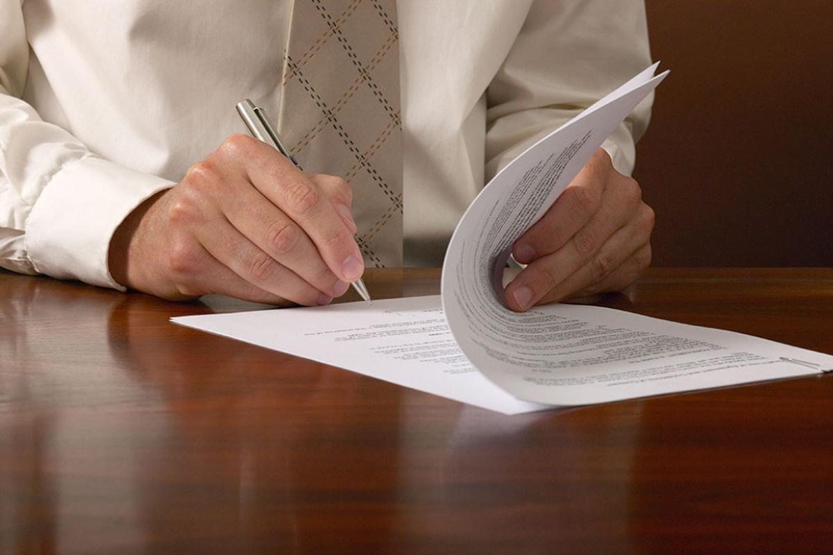 Person holding a pen and about to sign a contract