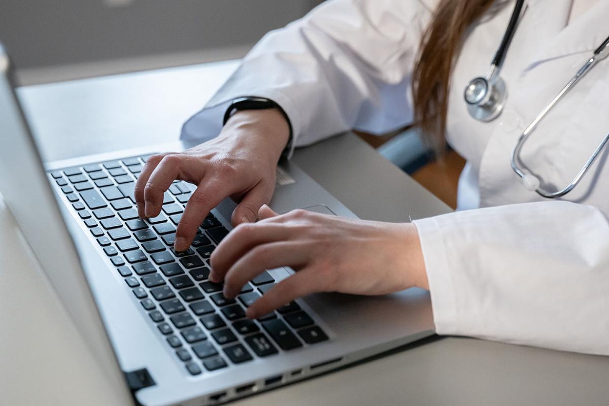 Close up of physician's hands typing on laptop keyboard