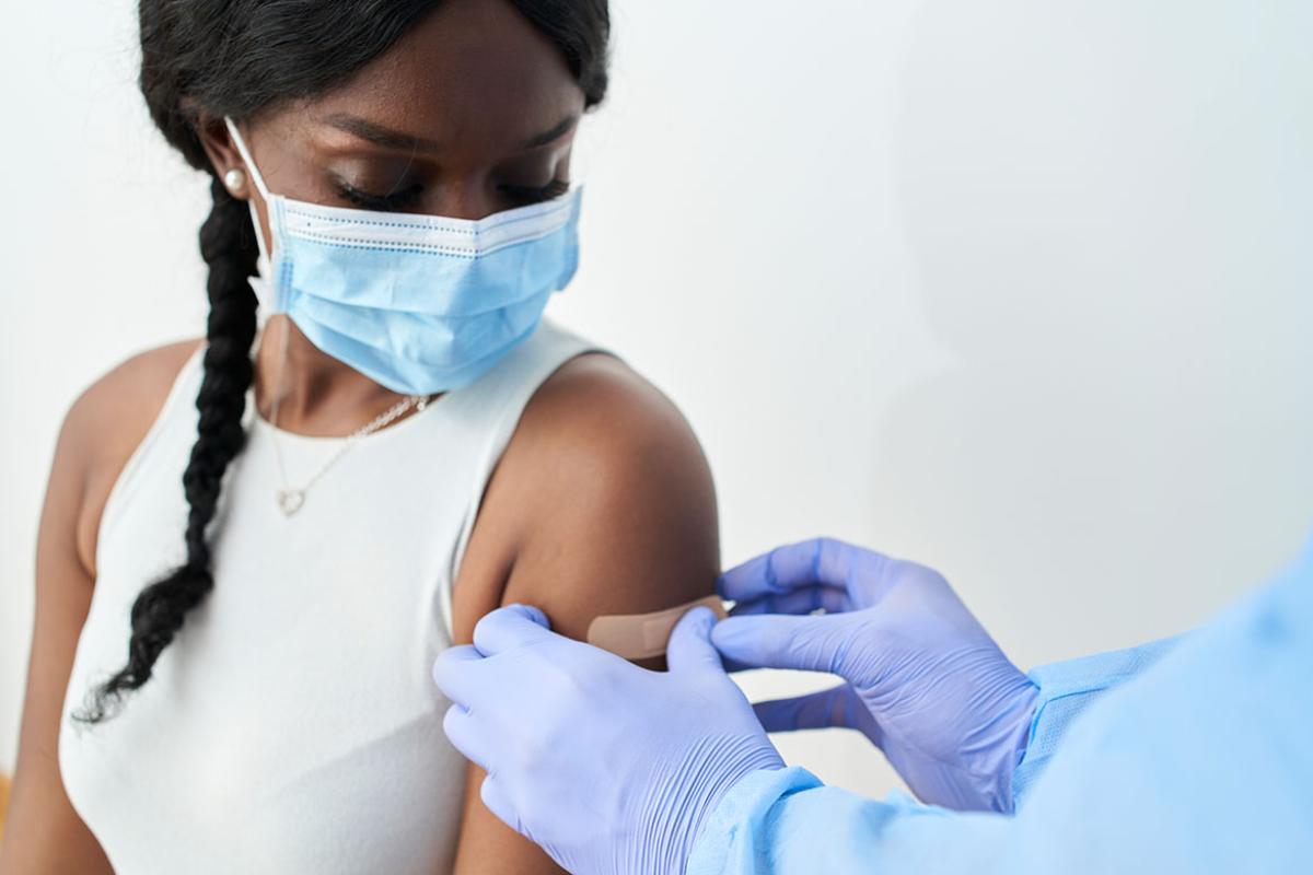 Health care worker applying bandage to a patient's arm after injection