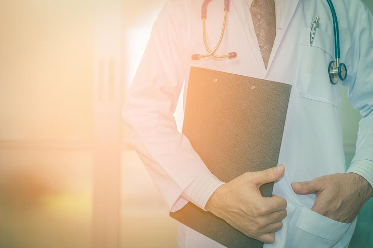 Midsection of physician holding a clipboard