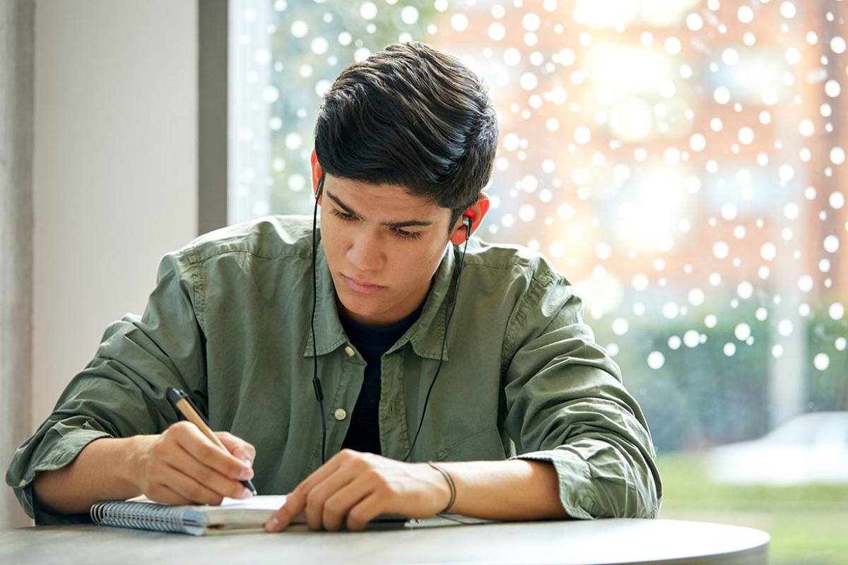 Young person wearing headphones studying at a desk