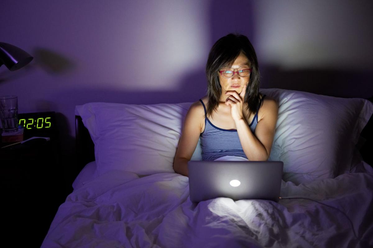 Person looking at laptop in bed during the early morning hours