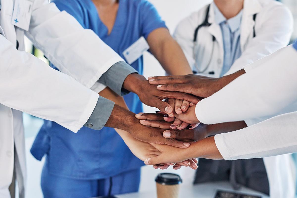 Group of medical practitioners joining their hands together in a huddle