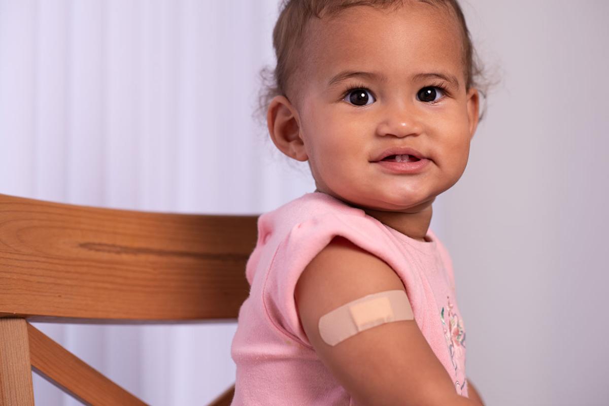Smiling baby with bandage patch on upper arm
