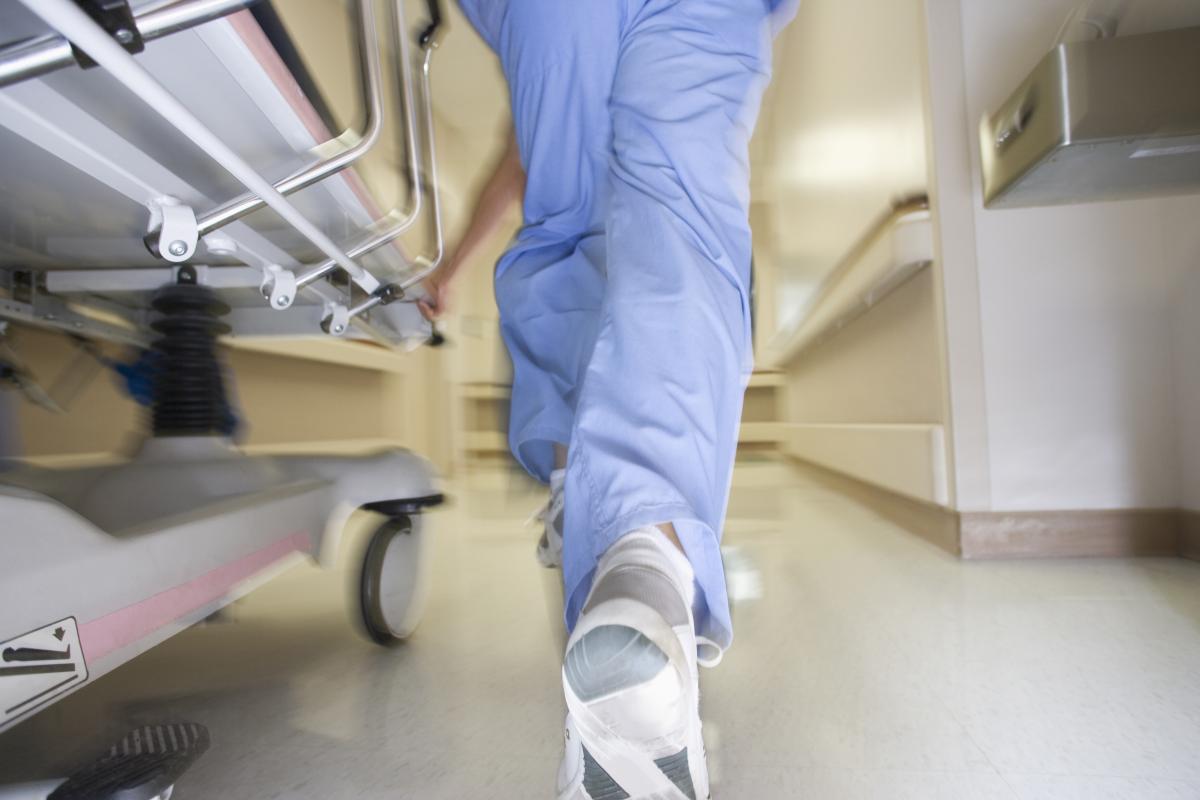 Health care professional walking next to a gurney