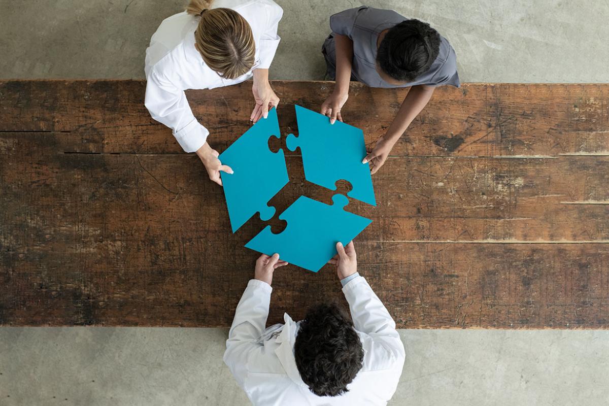 Three people assembling large puzzle pieces 