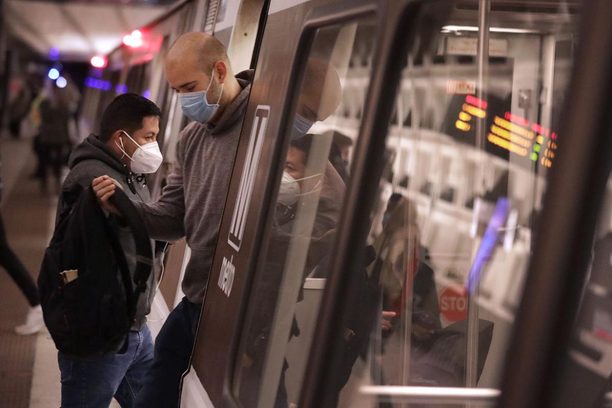 Masked riders enter and exit subway car during pandemic