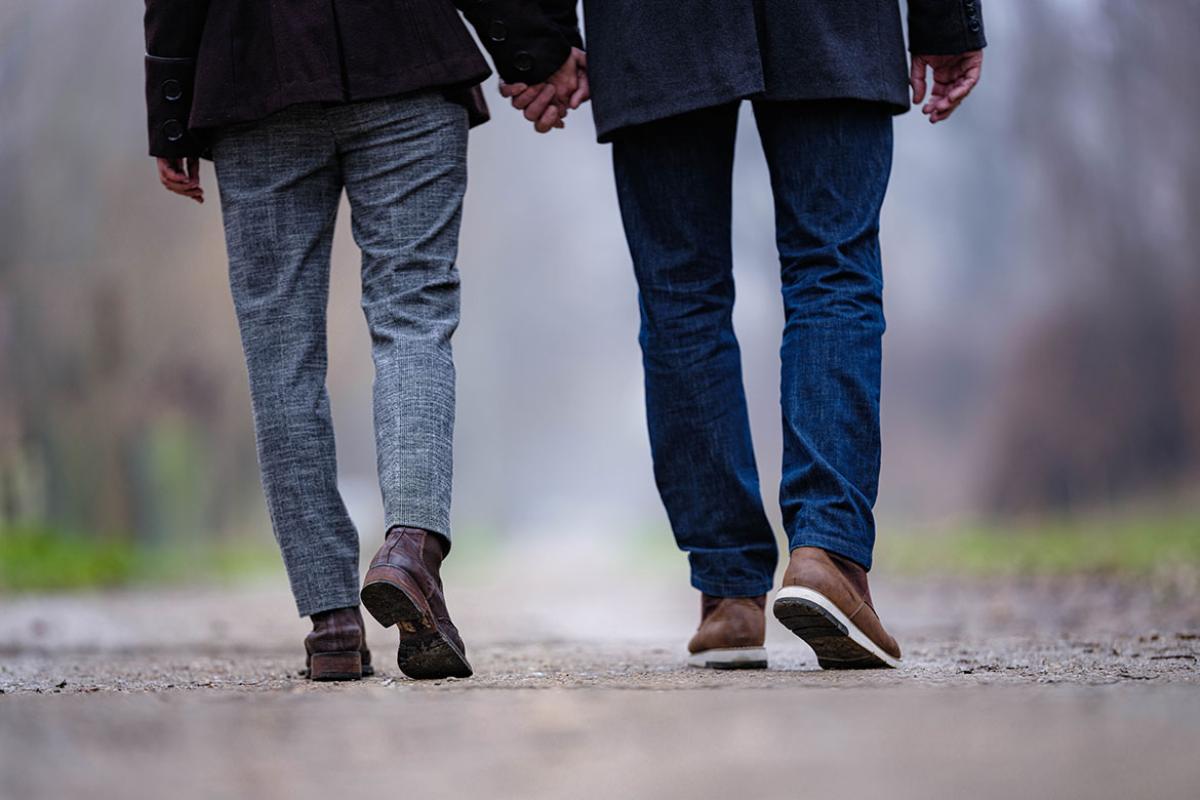 Back view of couple holding hands while walking in nature