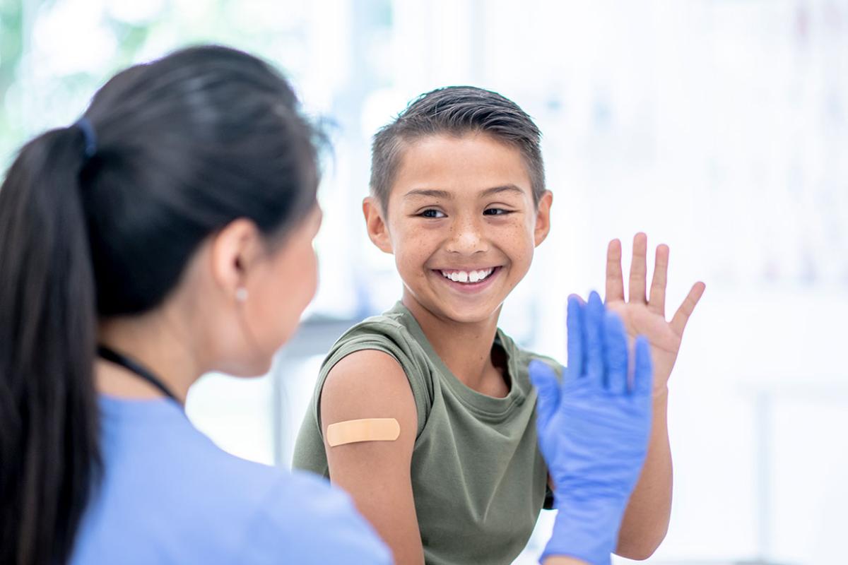 Smiling child getting ready to high-five a health care worker