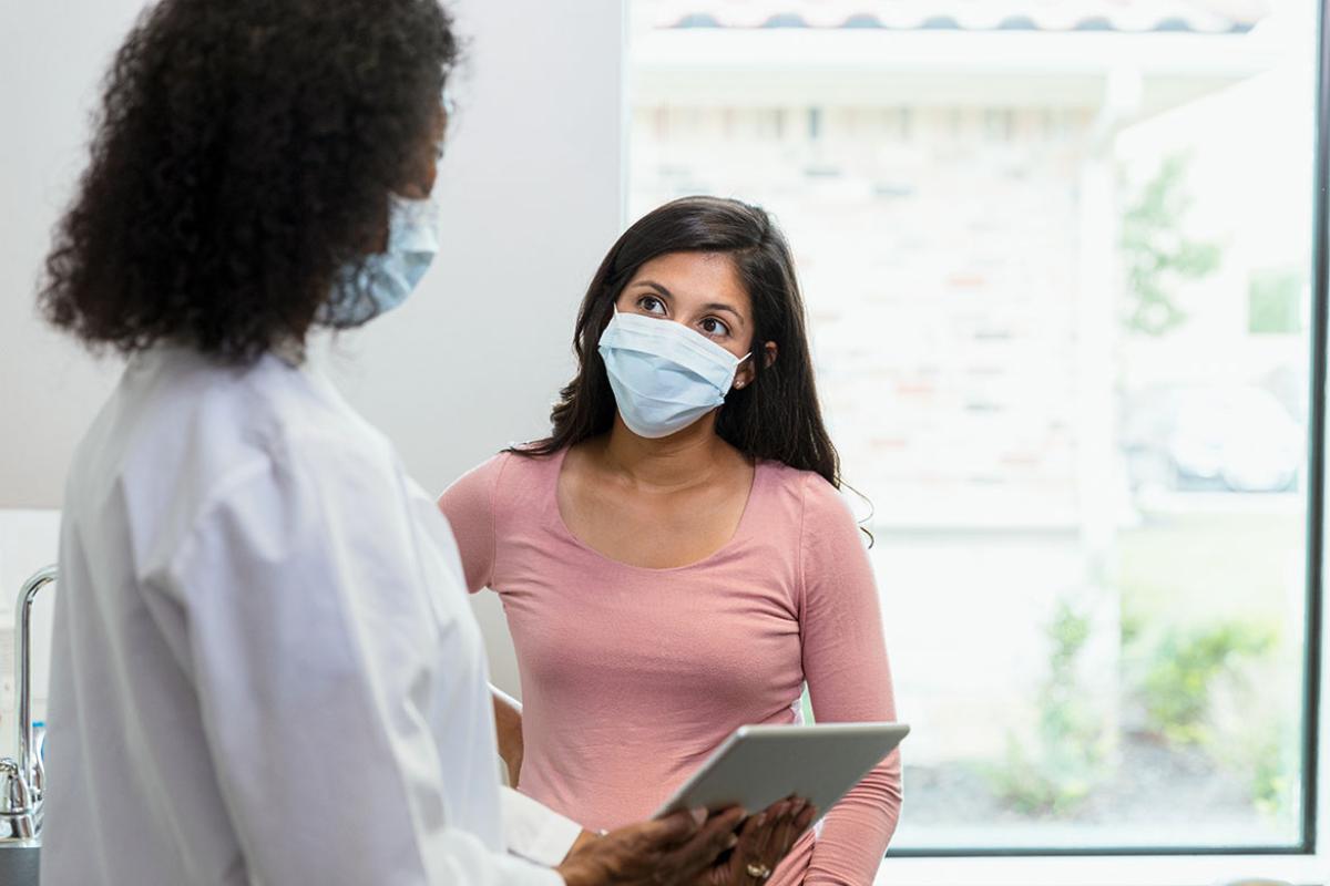 Patient with protective mask in discussion with physician