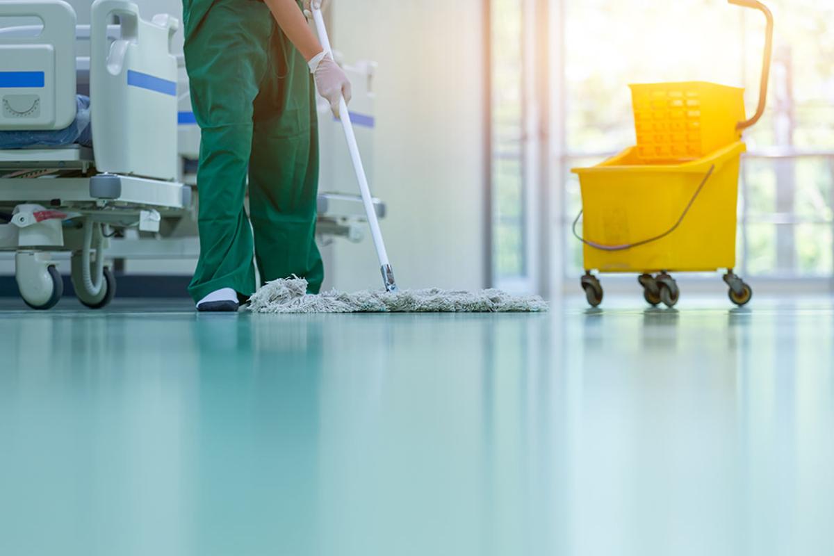 Person cleaning hospital floors, a janitor's bucket nearby