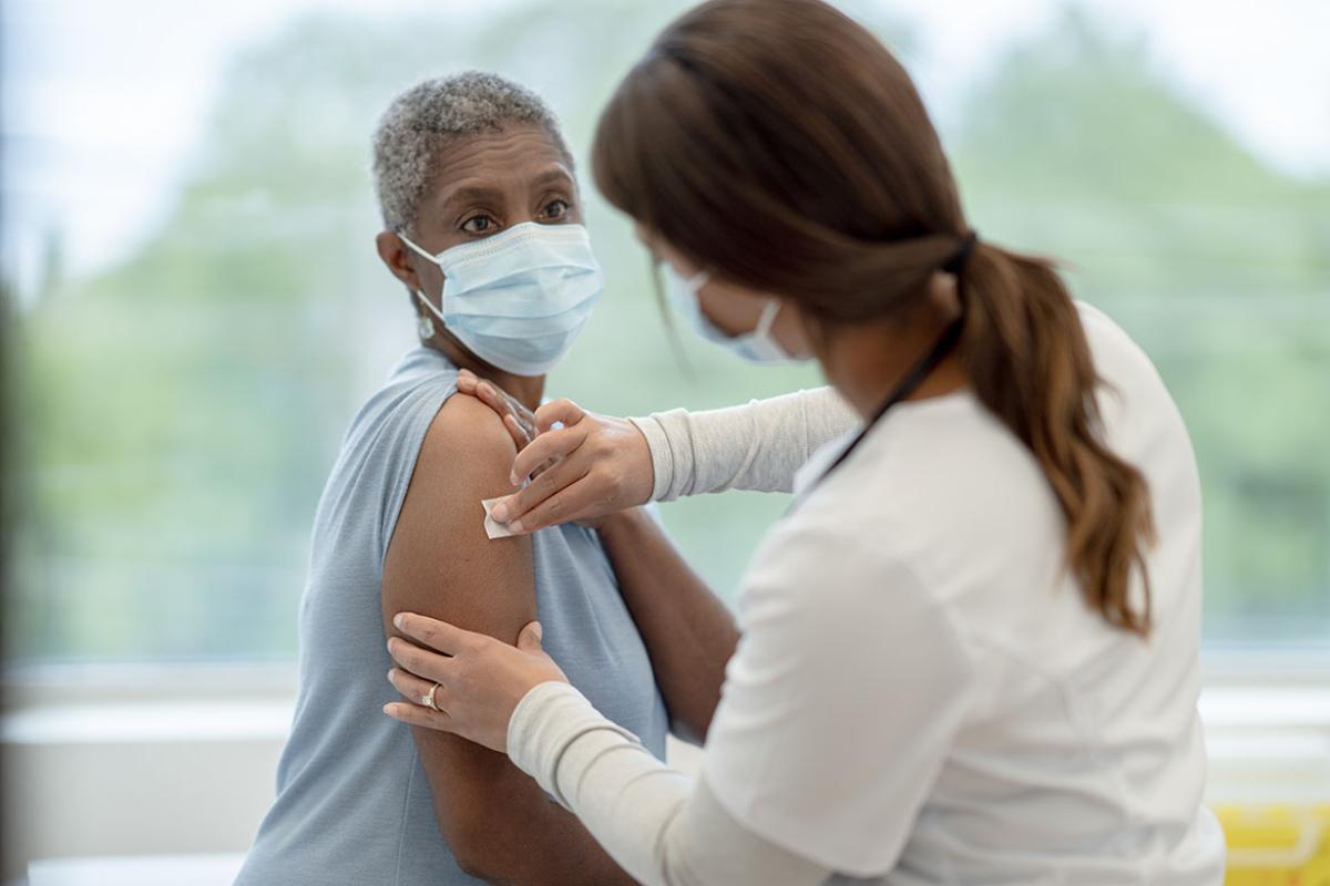Health care worker wiping down a patient's arm with an alcohol swab