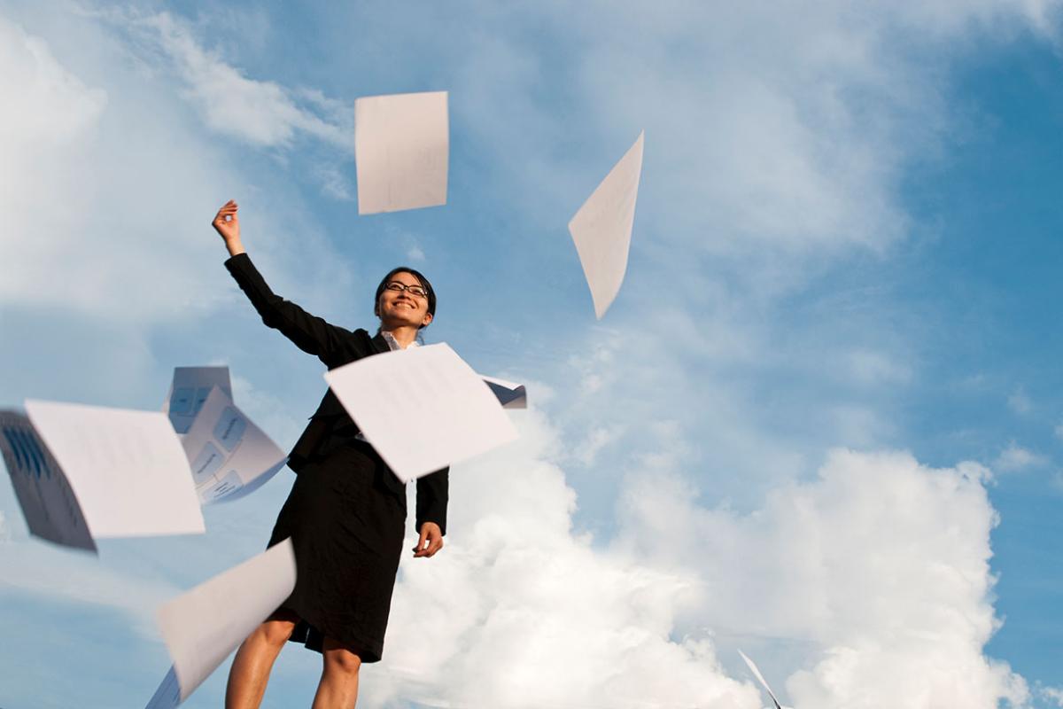 Smiling businessperson throwing papers in the air