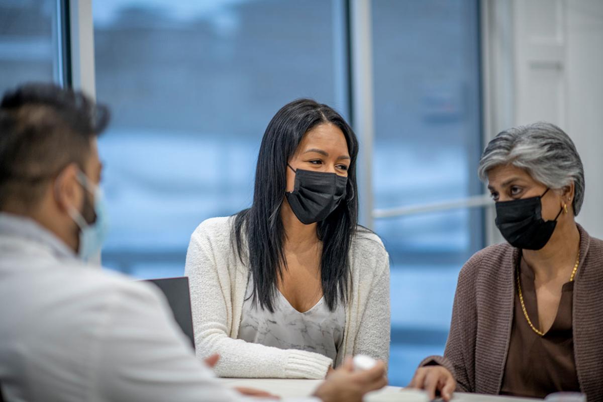People wearing masks in discussion at a table