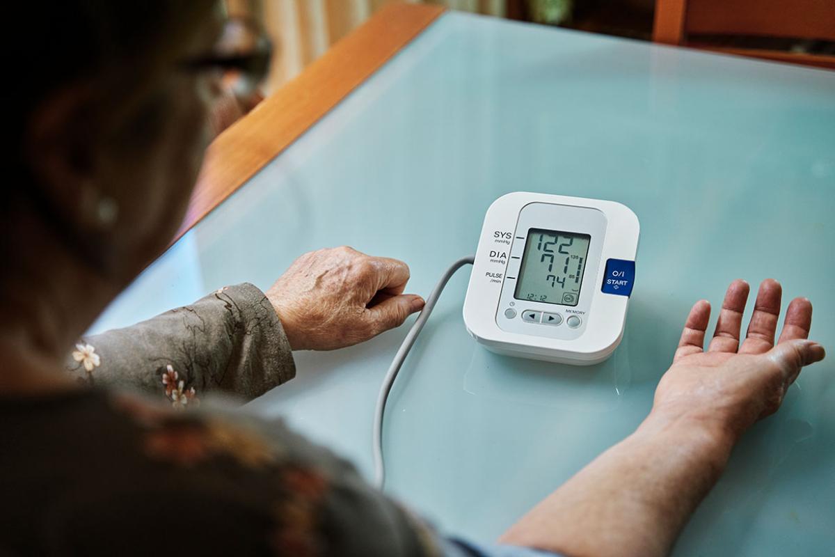 Person at a table measuring their blood pressure