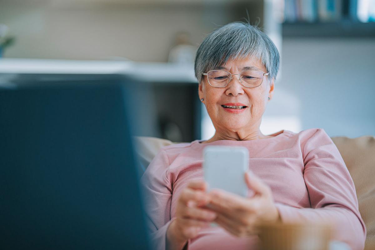 Smiling elderly person looking at smartphone