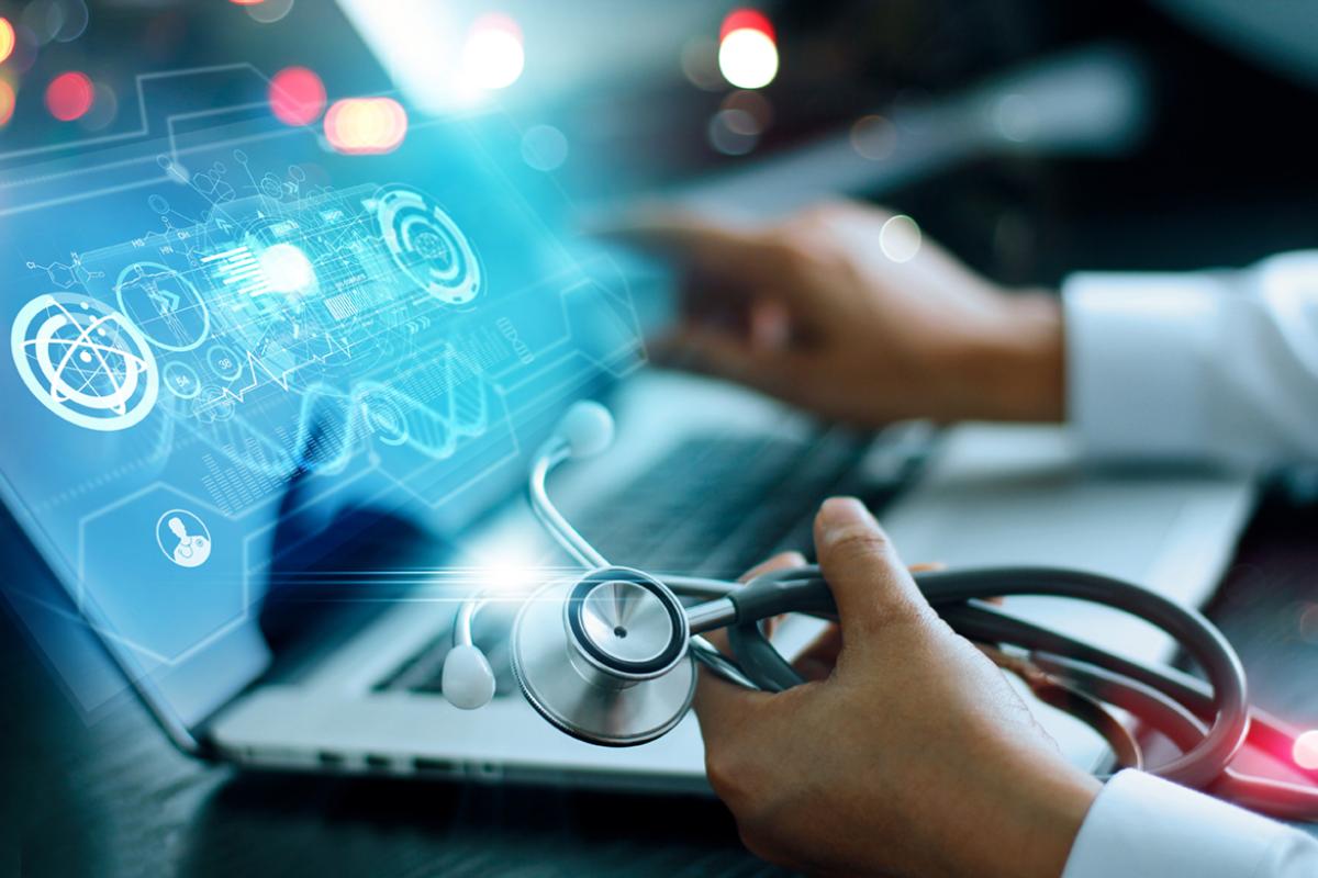 Physician hand with stethoscope, looking a futuristic image on laptop