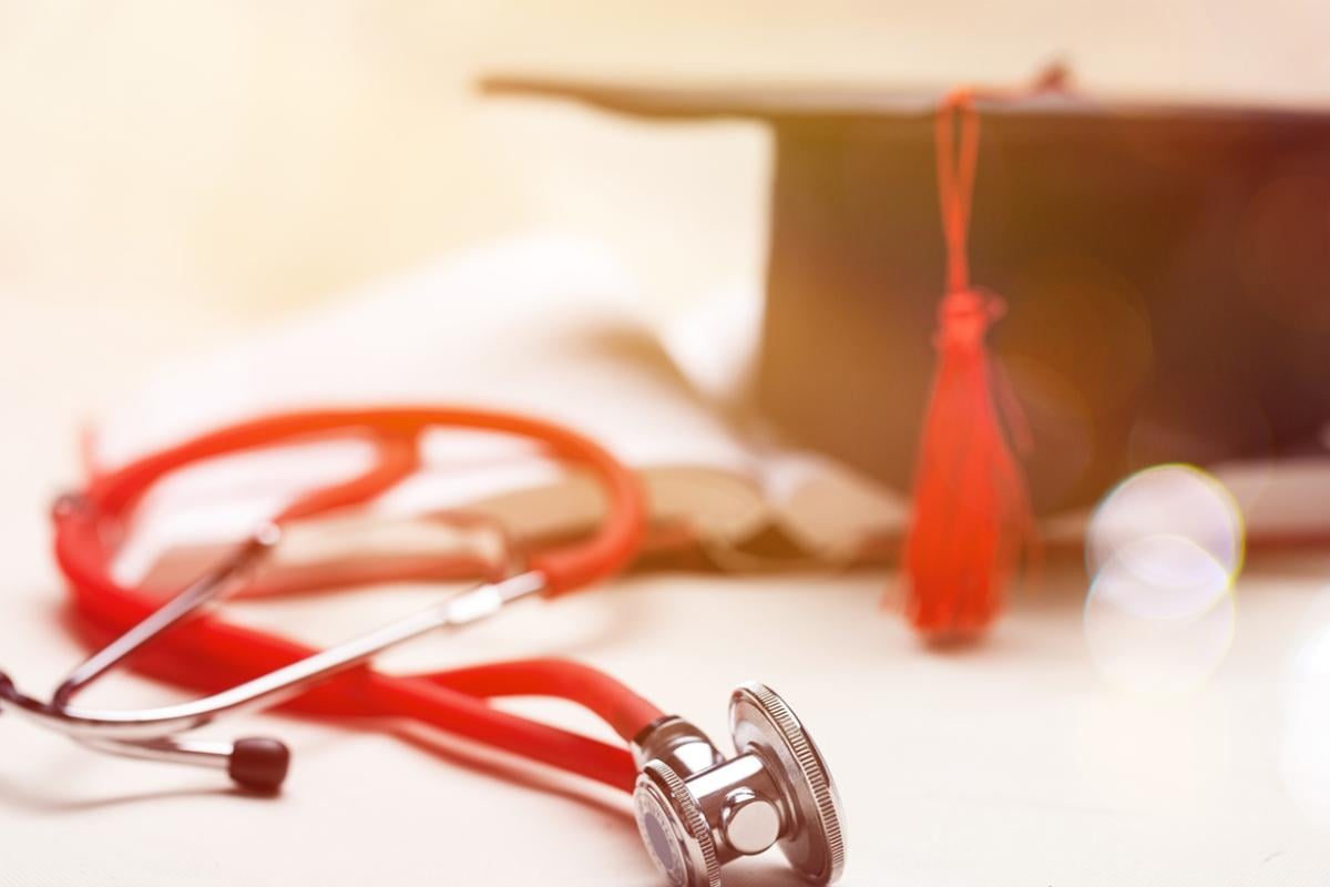 Red stethoscope with a book and graduation cap