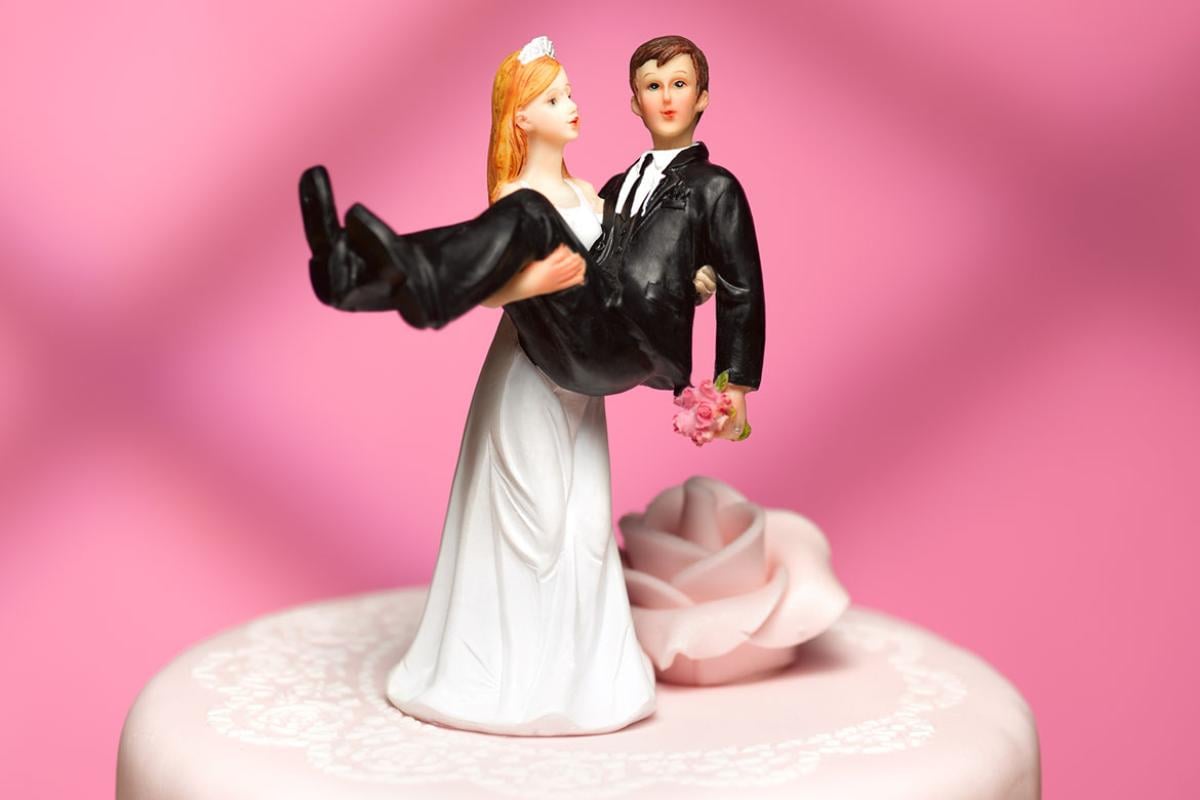 Bride holding groom on a wedding cake topper