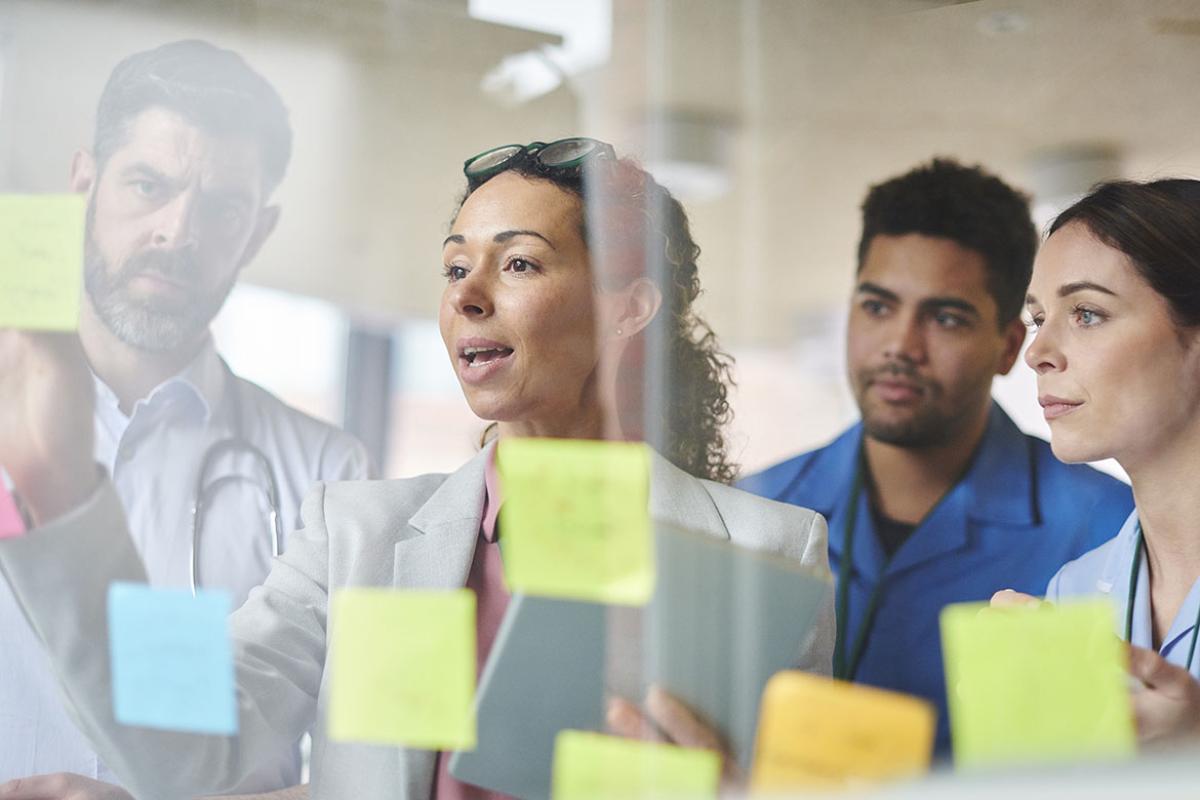 Physician team looking at post-its on glass wall