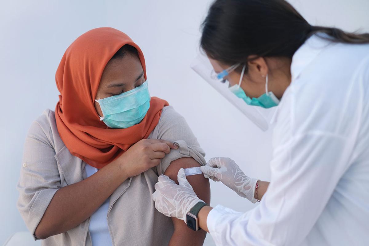 Doctor putting adhesive bandage to patient's arm