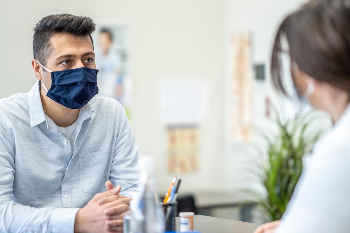 Masked patient speaking with health care worker