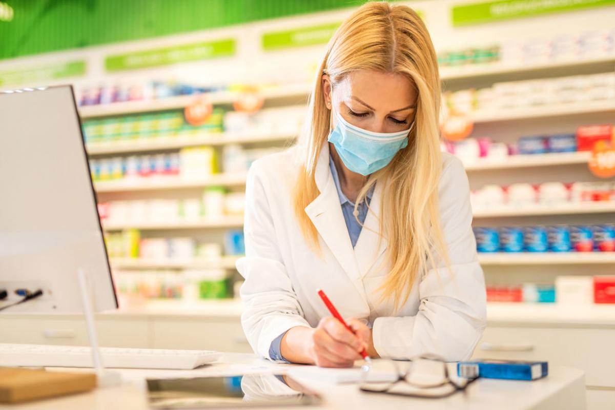 Pharmacist with protection mask prescribing medicine