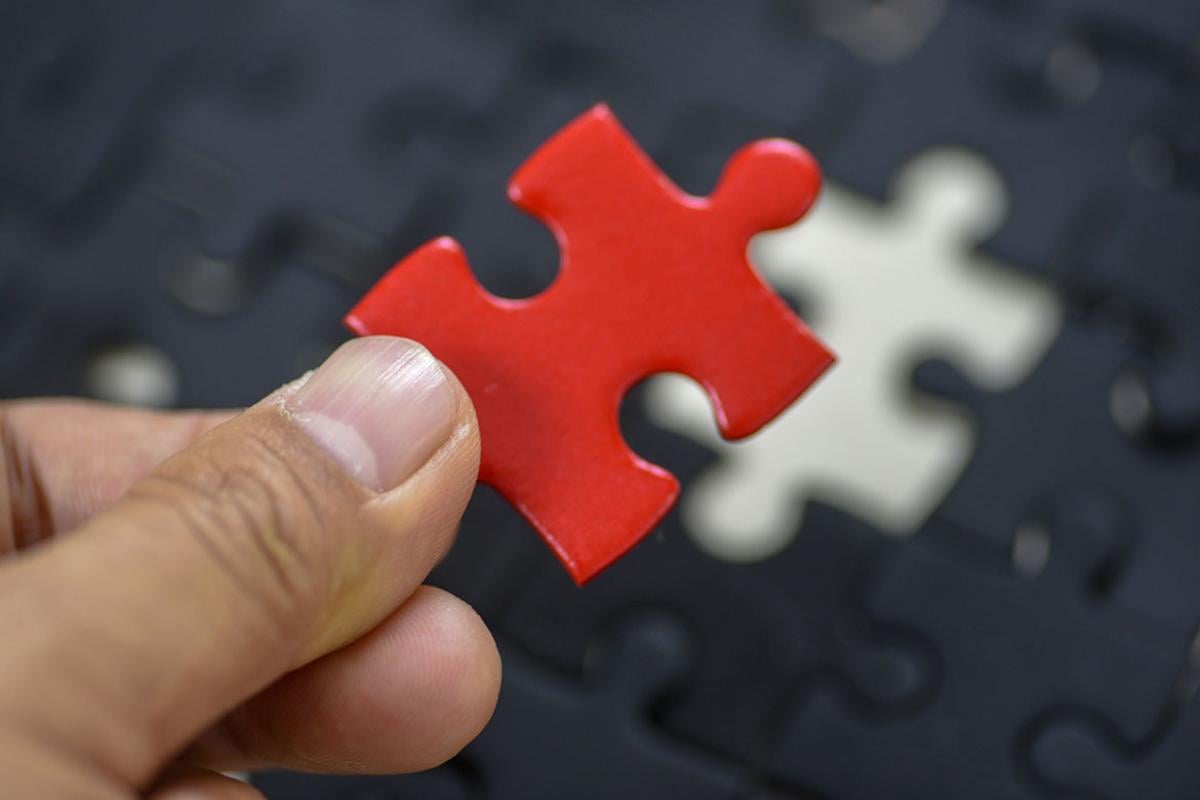 Person holding up a red puzzle piece