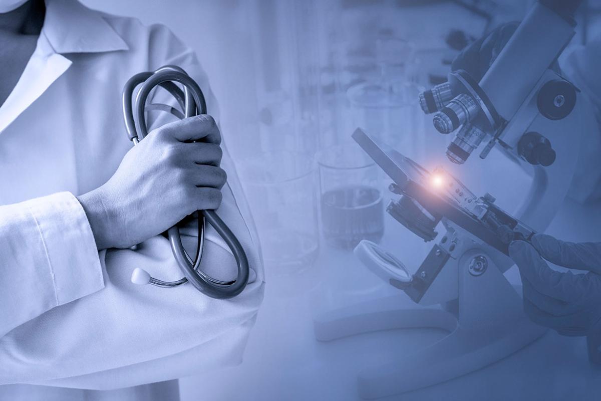 Doctor holds a stethoscope in hand with blurred background of microscope
