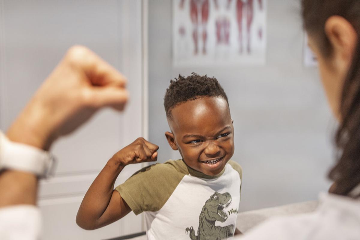 Smiling child flexing during an appointment with a doctor