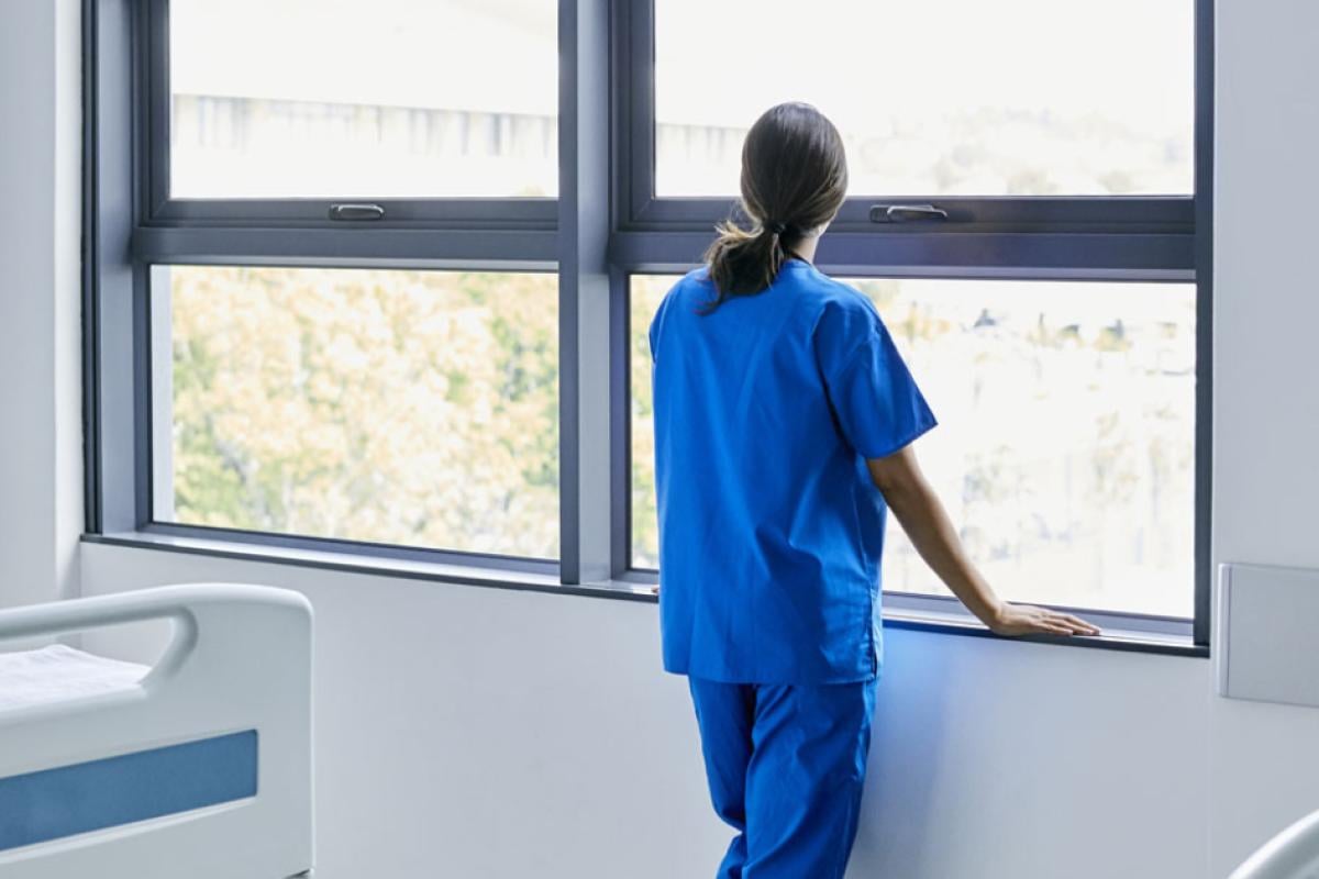 Female doctor in hospital room looking out the window