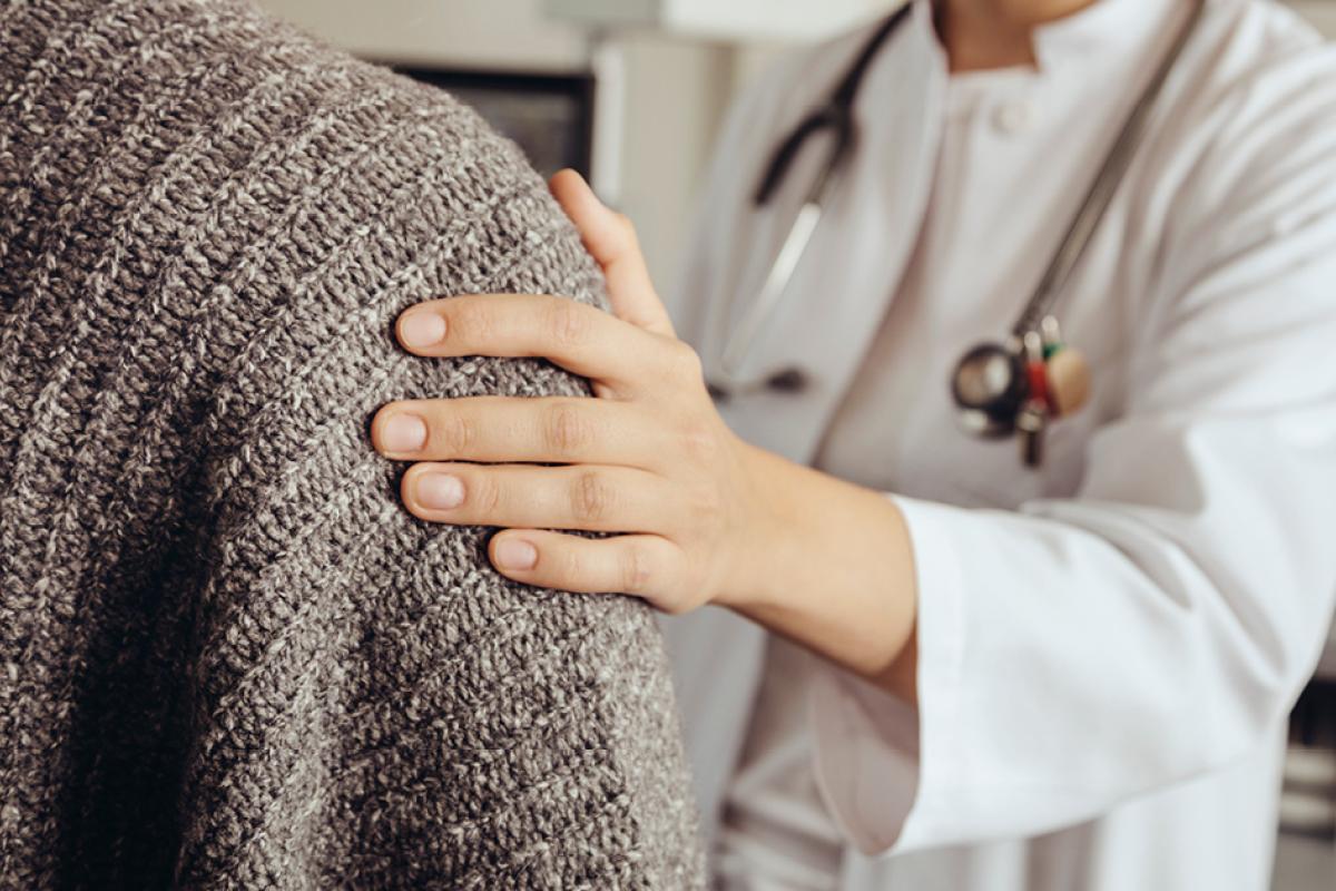 Physician placing a reassuring hand on the shoulder of a patient