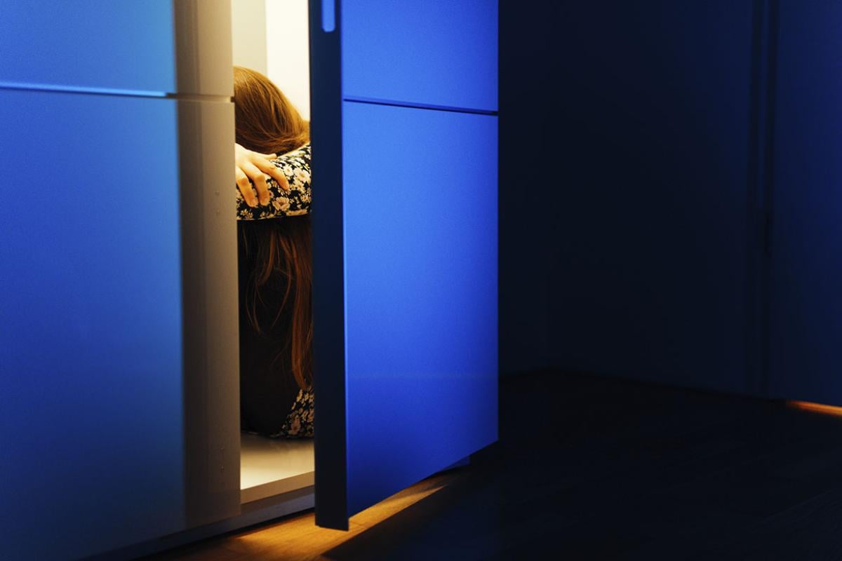 Person sitting in cabinet in the dark
