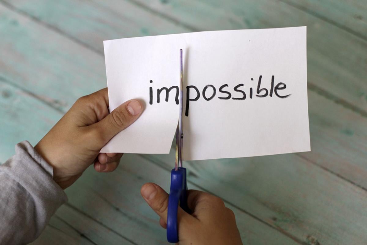 Piece of paper with the word "Impossible" being cut in half