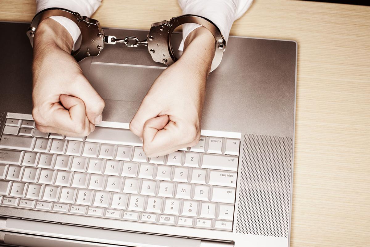 Handcuffed hands on keyboard