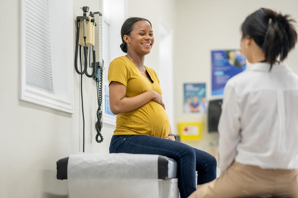 Smiling pregnant patient on an exam table in a doctors office