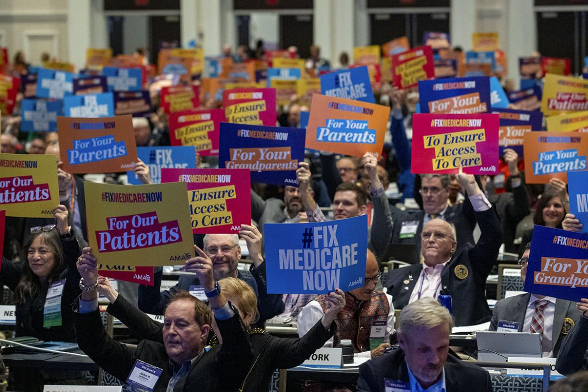 Delegates at the 2023 Interim Meeting of HOD hold "Fix Medicare Now" signs