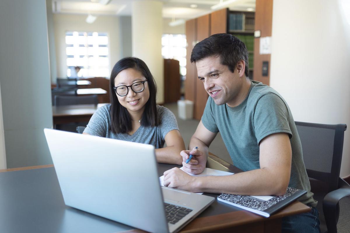 Two students working together at a laptop
