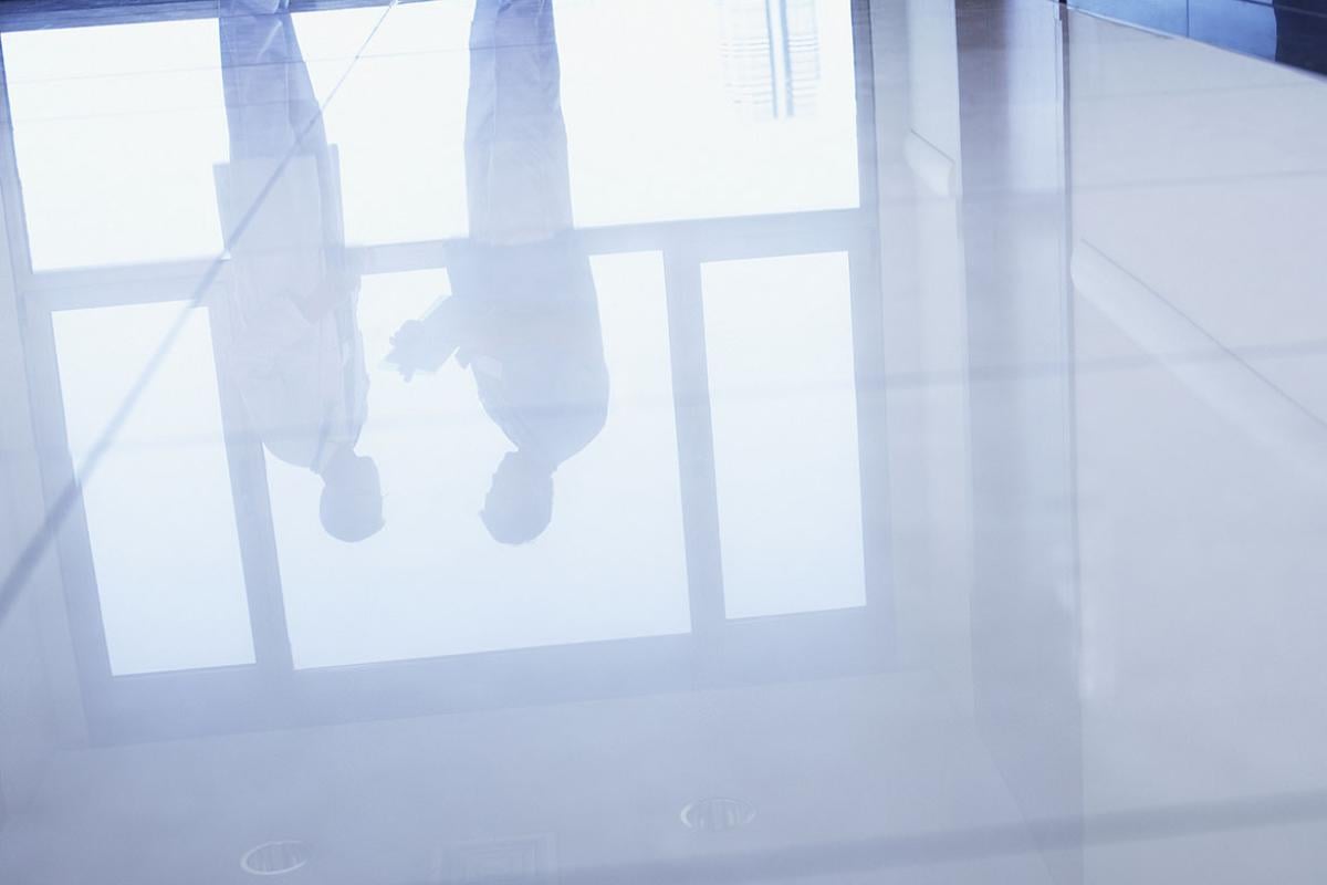 Reflection in floor of two doctors standing in hospital corridor