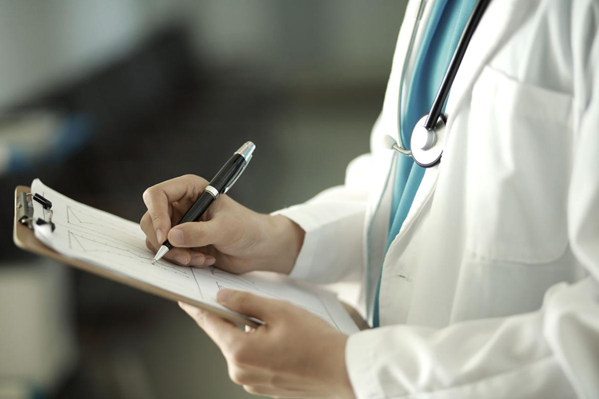 Physician writing on clipboard