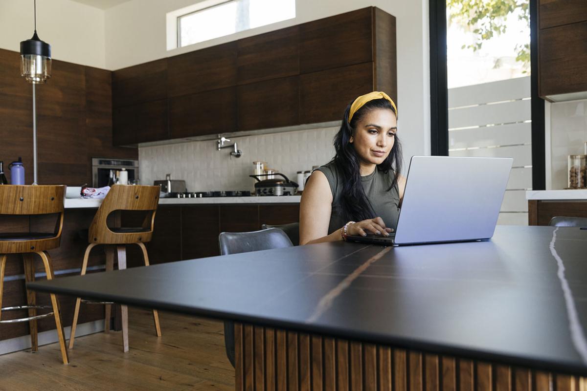 Person sitting in kitchen and working at laptop