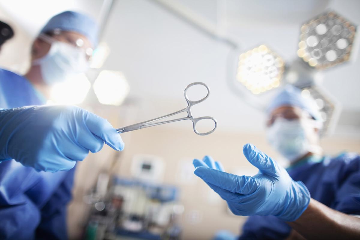 Surgeon passing medical equipment tool in surgery operating room