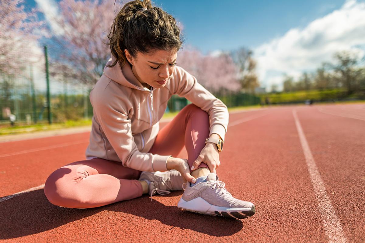 Athlete with a pained expression holds ankle