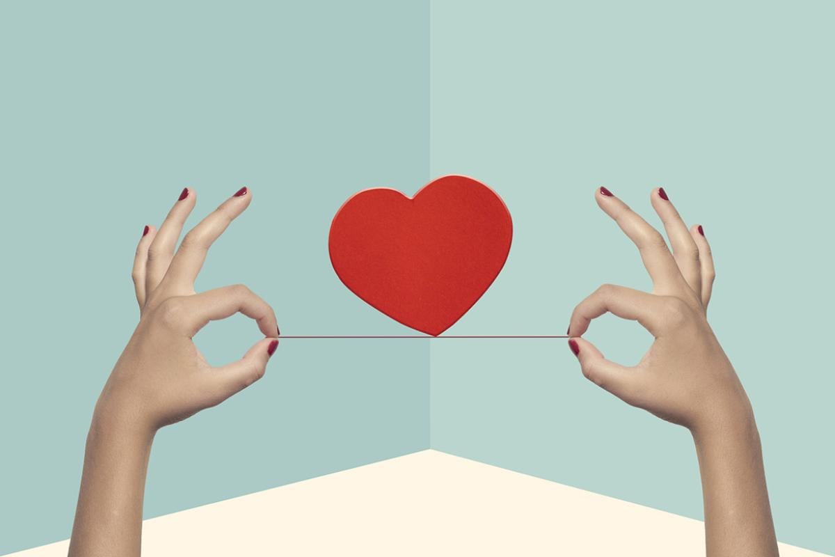 Heart balanced on a string held by two hands