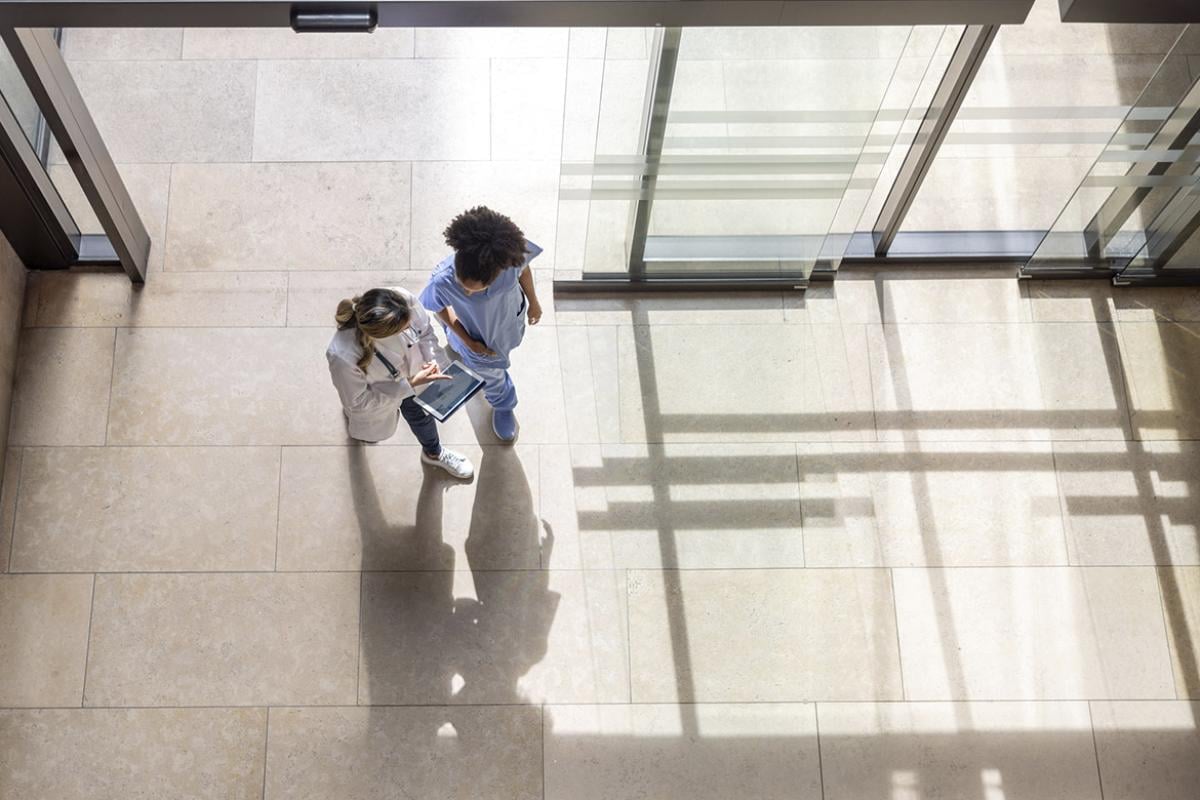 Doctor looking at test results with a colleague on a digital tablet while walking at the hospital