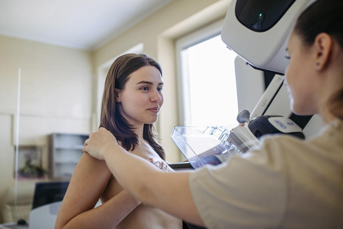 Healthcare worker talking with patient during mammogram screening