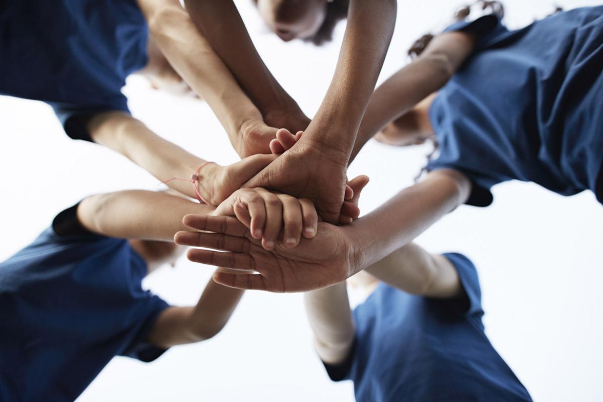 Group of people stack hands in a huddle