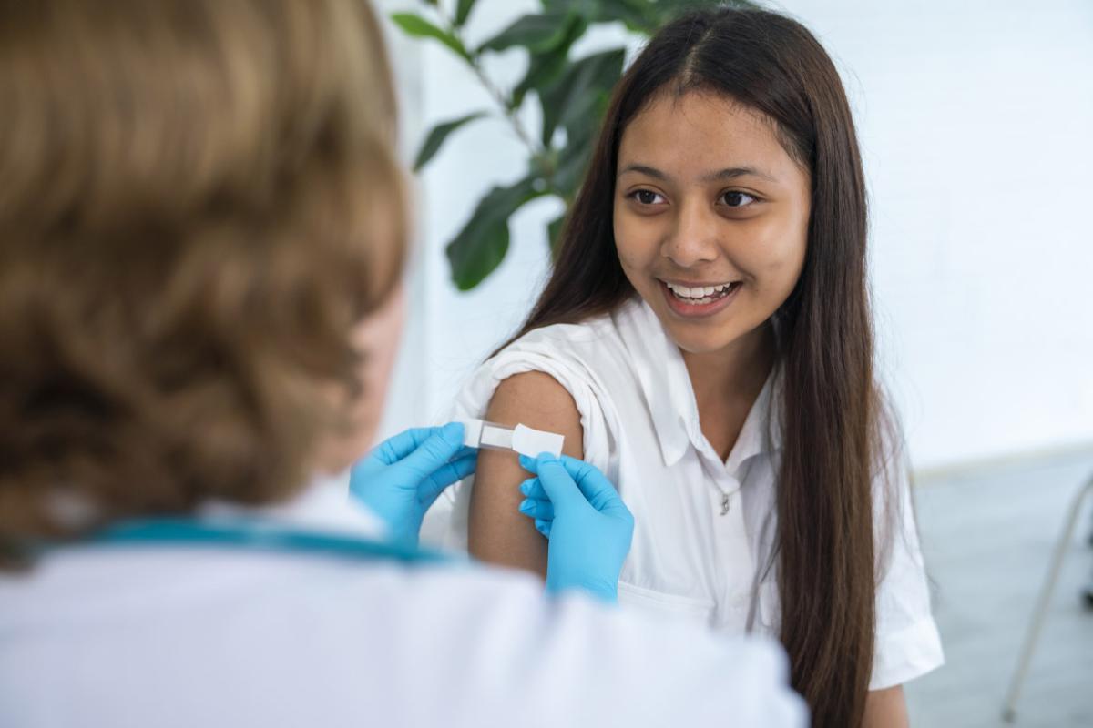 Adhesive bandage applied to upper arm of smiling young patient