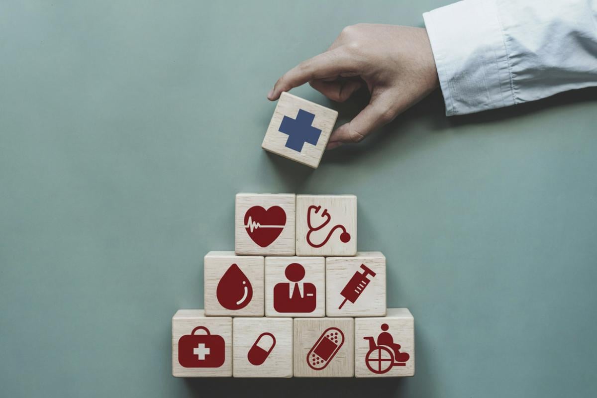 Hand stacking blocks with health care icons