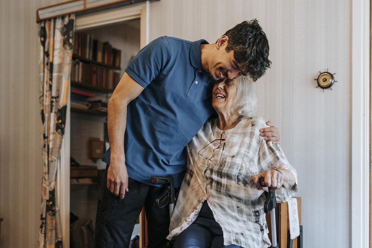 Smiling caregiver embraces older smiling patient